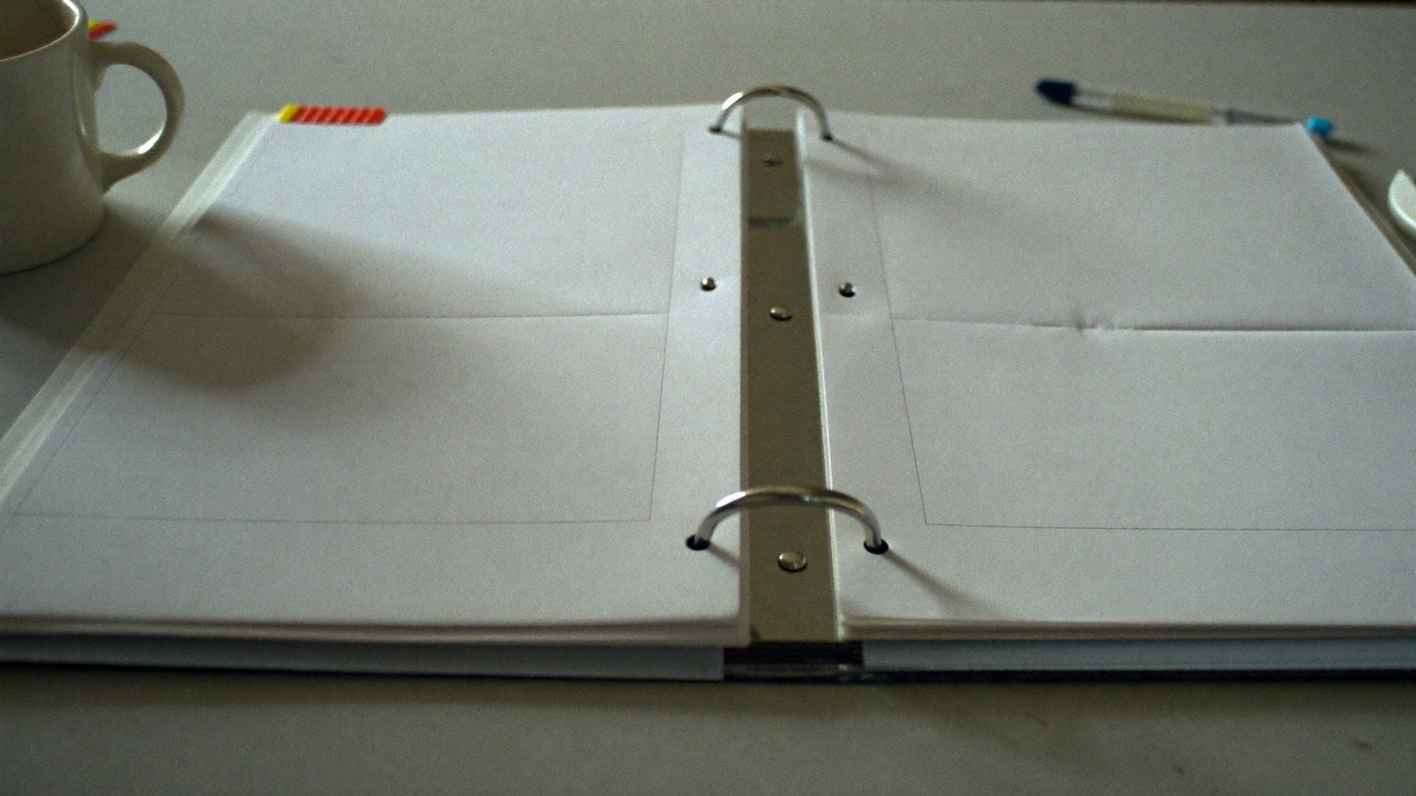 Aufgeschlagener Ringordner mit leeren Registerblättern, Stift und Tasse auf einem Seminartisch